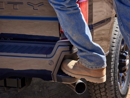 2024 Ford Super Duty close up view of a man stepping on the rear corner bumper step