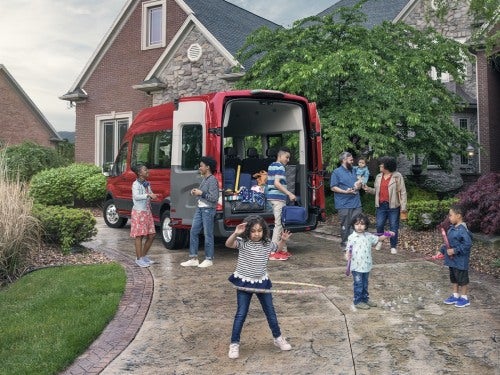 2024 Ford Transit parked at a home with a large family standing outside about to load into vehicle