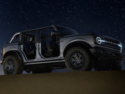 2024 Ford Bronco parked on a sand dune at night under the stars