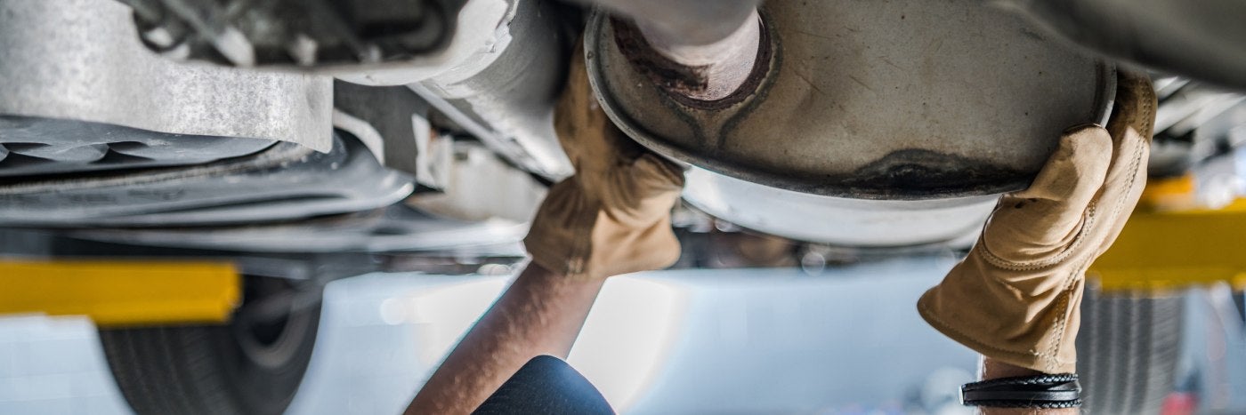 view of service tech inspecting a vehicle's catalytic converter